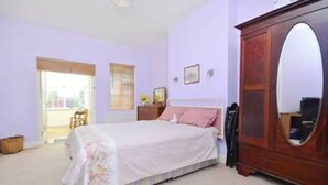 A bedroom with a bed, a wooden wardrobe, and a large mirror. - Quite Garden Flat with parking (London)