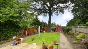 A garden with a paved patio, a wooden fence, and a variety of potted plants. - Quite Garden Flat with parking (London)