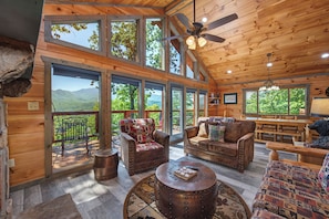 A spacious cabin with large windows, wooden interior, and a cozy seating area.