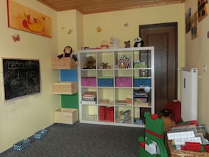 A children's playroom with a bookshelf, toys, and a chalkboard.