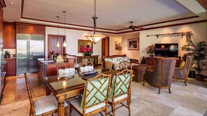 A spacious living area with a dining table, chairs, a television, and a kitchen area with a refrigerator.