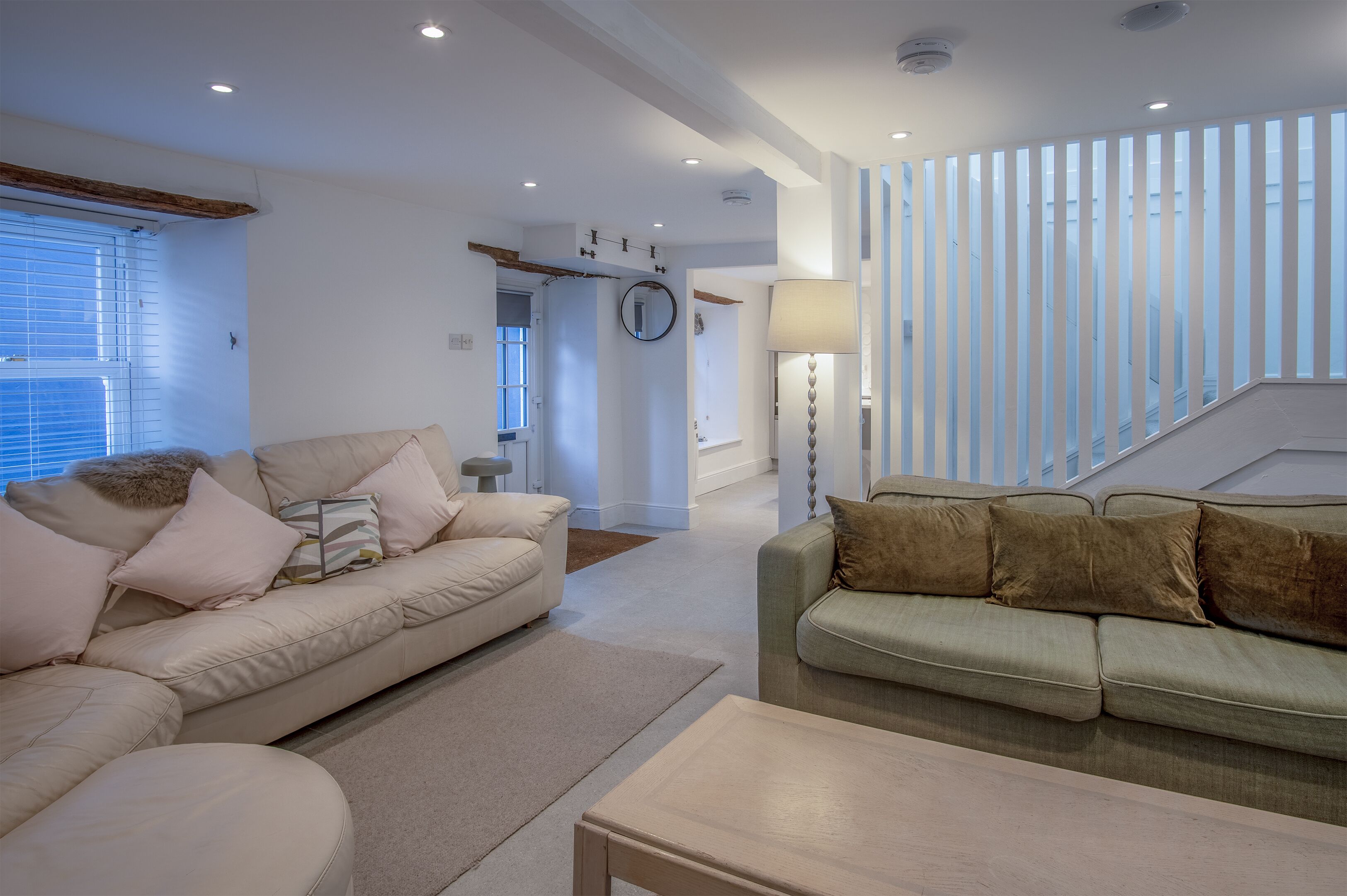 A spacious living room with two sofas, a coffee table, and a staircase leading to an upper level.
