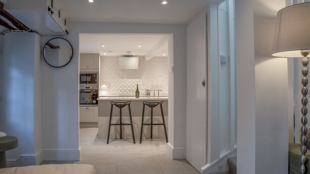 Une cuisine moderne dotée d’un îlot central, de deux tabourets de bar et d’un luminaire suspendu.