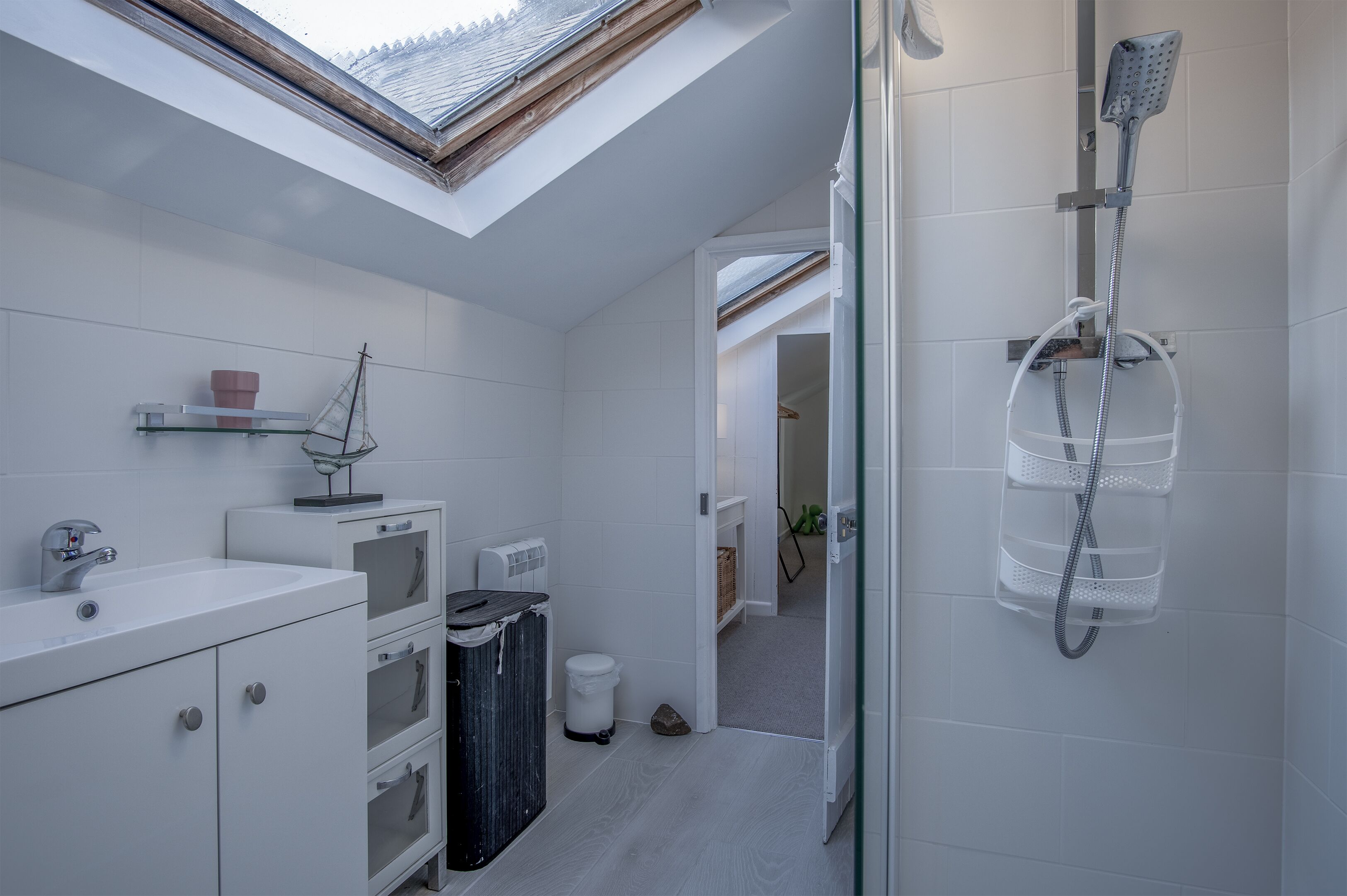 A modern bathroom with a skylight, a shower, and a sink.