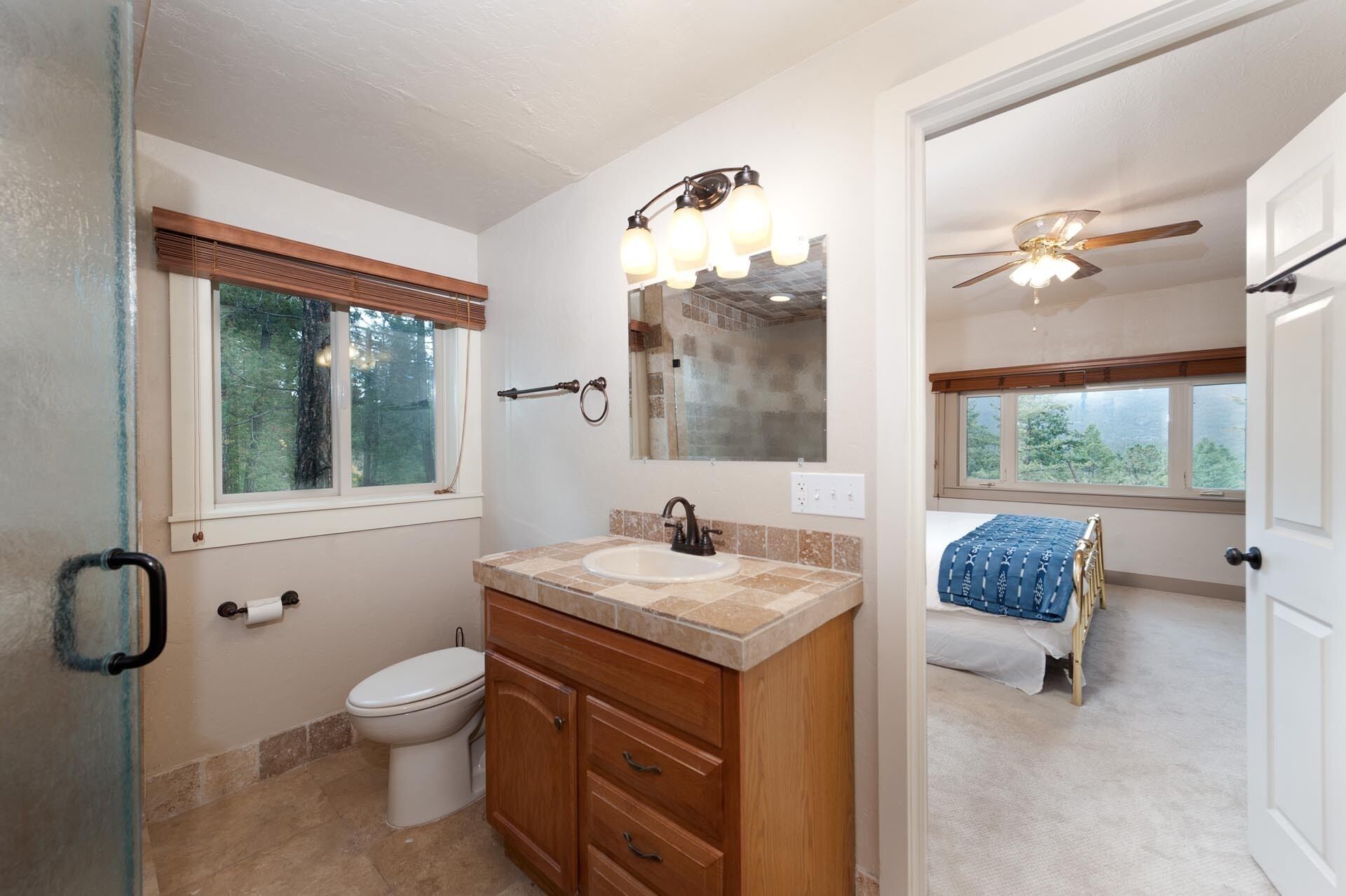 Une salle de bain équipée de toilettes, d’un lavabo, d’un meuble-lavabo et d’un ventilateur de plafond.