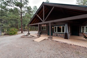 A rustic lodge with a covered porch, stone walls, and a gravel driveway.