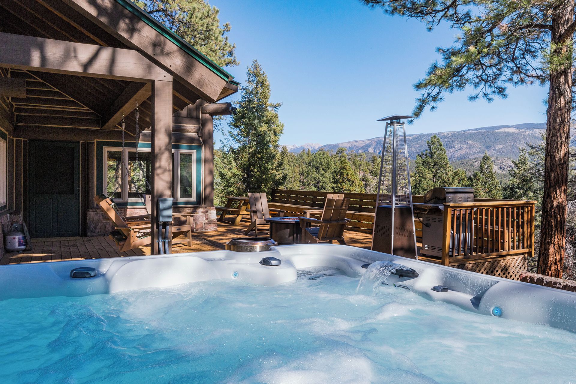 Un área de hidromasaje con terraza de madera, mobiliario exterior y vistas a la montaña.