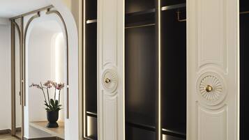 Un intérieur moderne avec un escalier menant à une pièce sombre, une plante en pot et une porte décorative dotée d’une poignée en laiton.