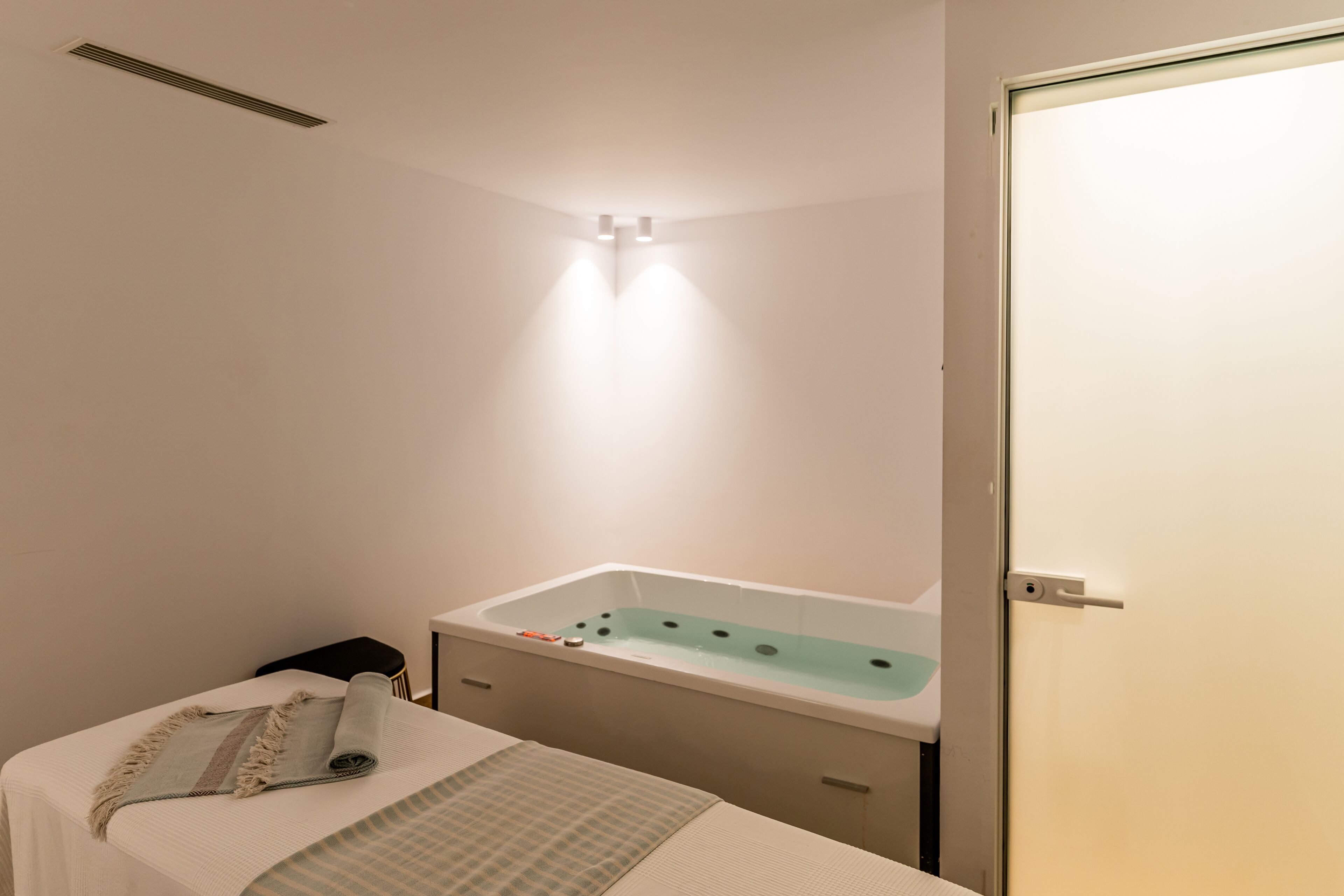 Ein modernes Badezimmer mit einer Badewanne, einem kleinen Tisch mit einem Handtuch und einer Tür.