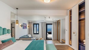 A modern hotel room with a large bed, a desk, and a view of the sea. - Cresanto Luxury Suites  (Santorini)