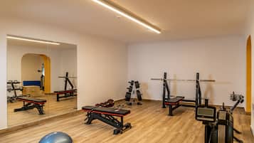 Een sportschool met trainingsapparatuur, een spiegelwand en een houten vloer.