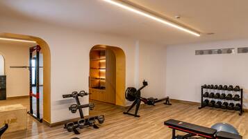 A gym with exercise equipment, a squat rack, a bench, and a rack of dumbbells.