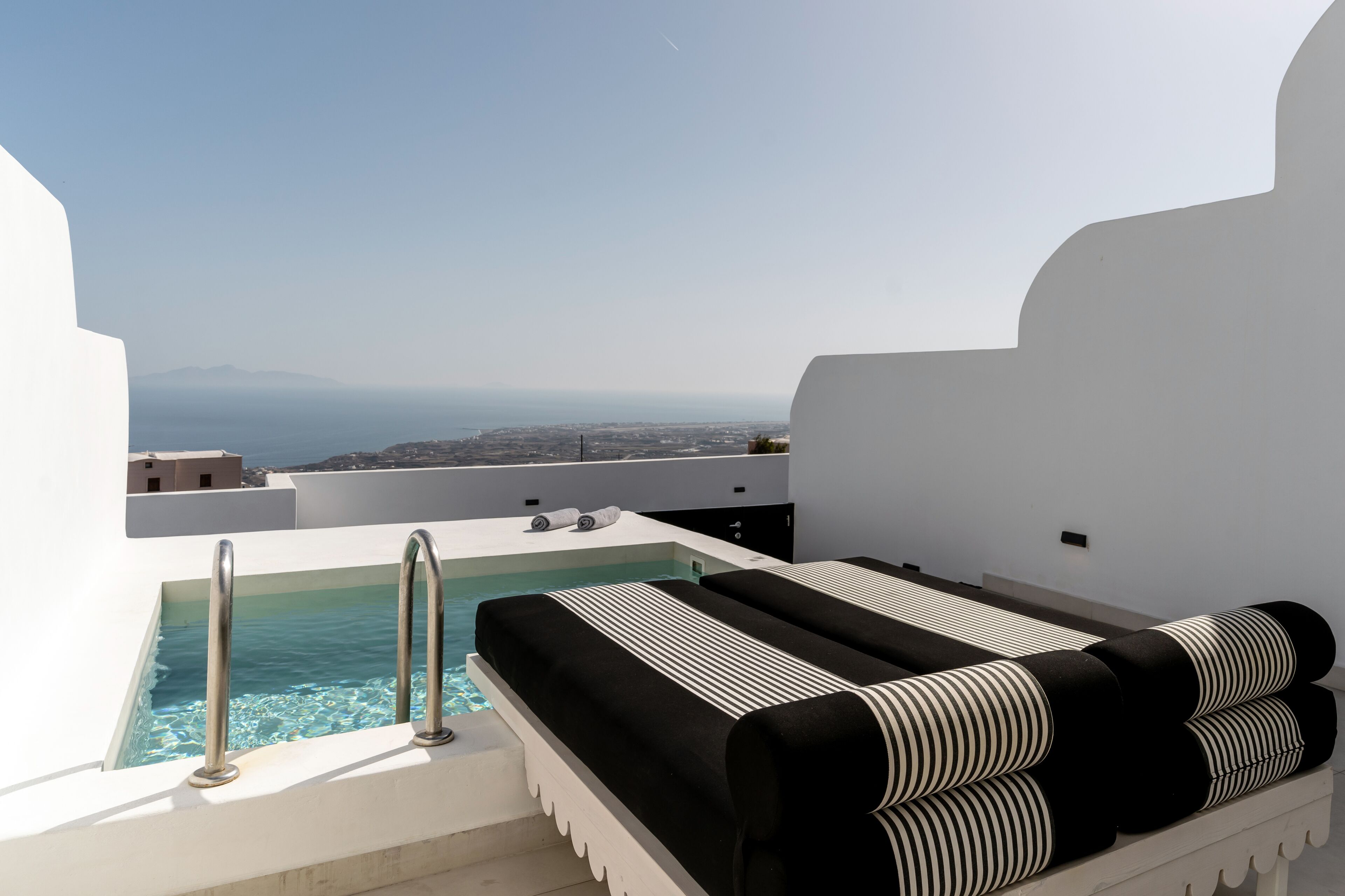 Eine Dachterrasse mit Pool, Lounge-Bereich und Blick auf Stadt und Meer.