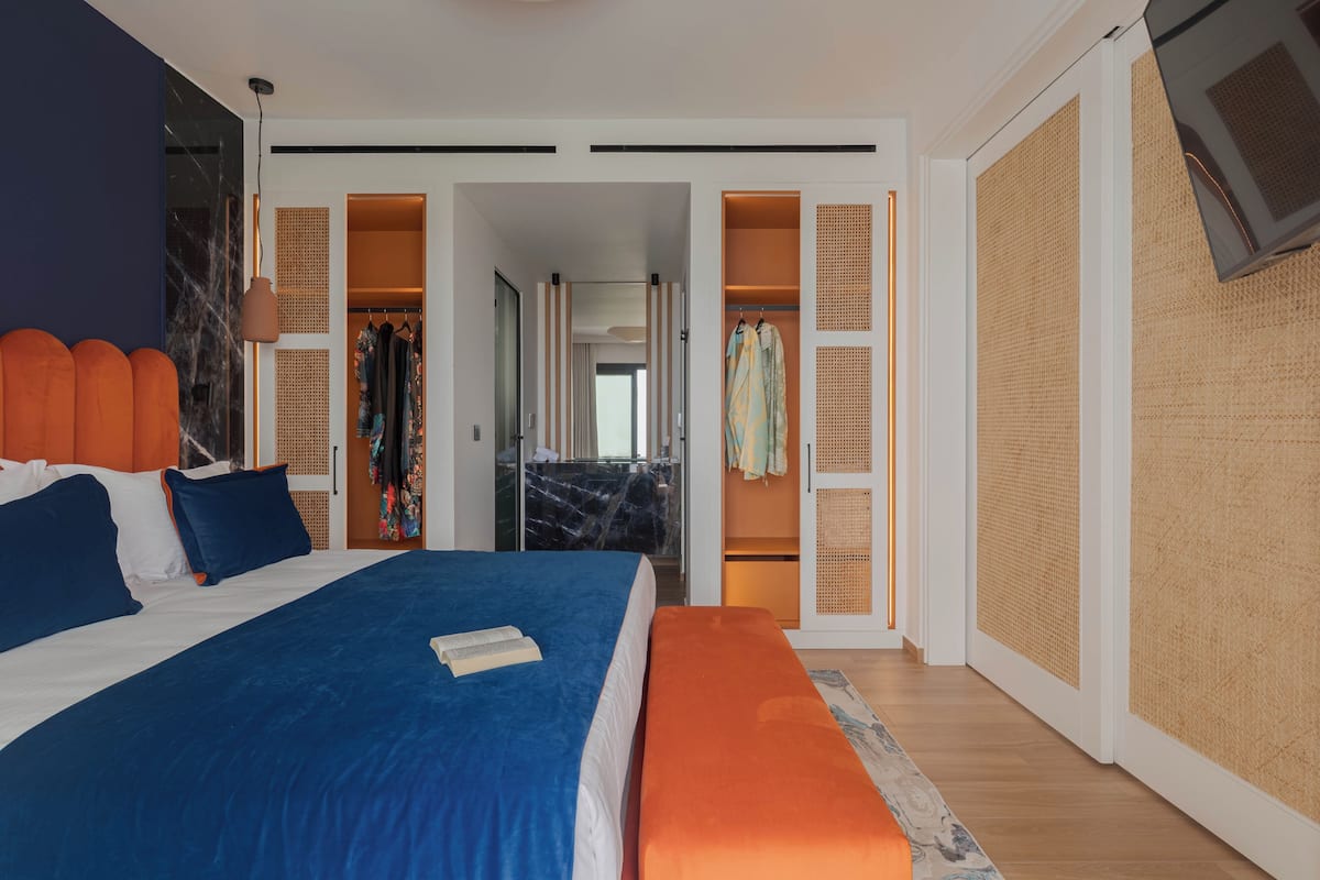 Ein modernes Hotelzimmer mit einem großen Bett, einer Bank, einem Kleiderschrank und einem begehbaren Kleiderschrank.