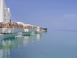 Una piscina al aire libre, sombrillas, sillones reclinables de piscina