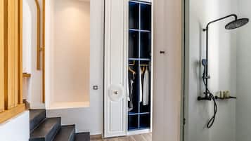 Un baño moderno con ducha, un vestidor con ropa y una escalera de madera.
