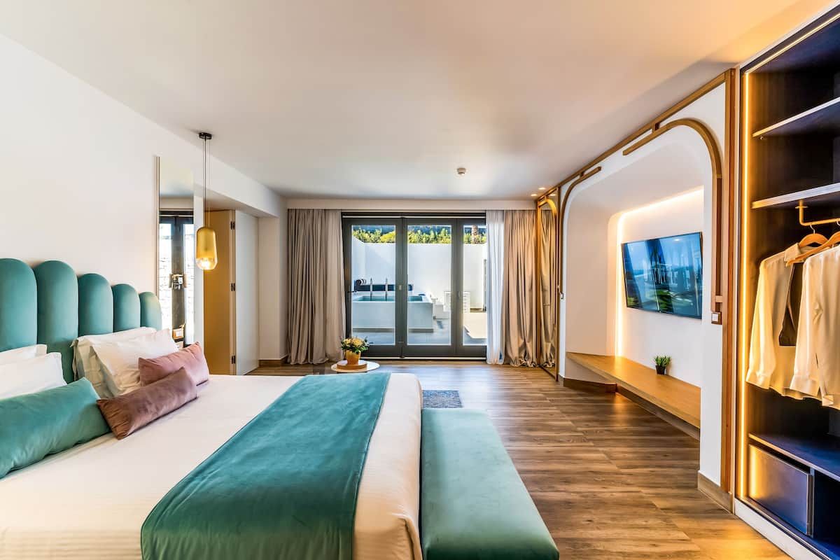 Ein modernes Hotelzimmer mit einem großen Bett, einer Bank, einem Fernseher und einem Kleiderschrank.
