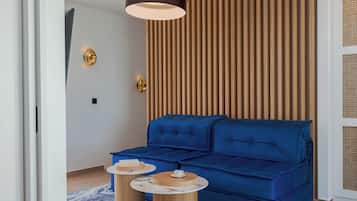 A modern living room with a blue sofa, two wooden side tables, a marble-patterned rug, and a wooden slatted wall.