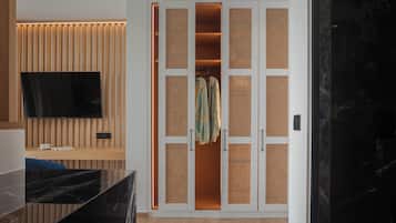 A modern room with a wooden panel wall, a flat-screen TV, a black marble countertop, and a walk-in closet with woven partitions.