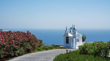 A white church with blue domes and a clear view of the sea in the background.