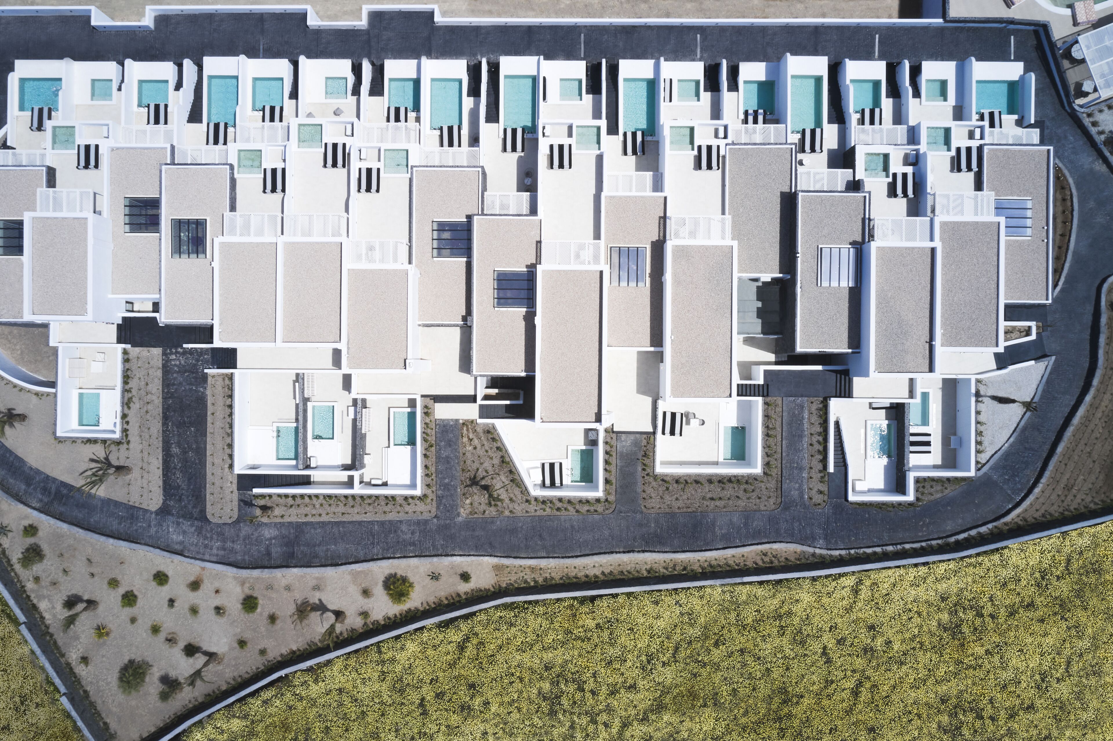 An aerial view of a modern hotel with multiple rectangular buildings, each with balconies and swimming pools.