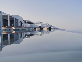 Una piscina al aire libre, sombrillas, sillones reclinables de piscina