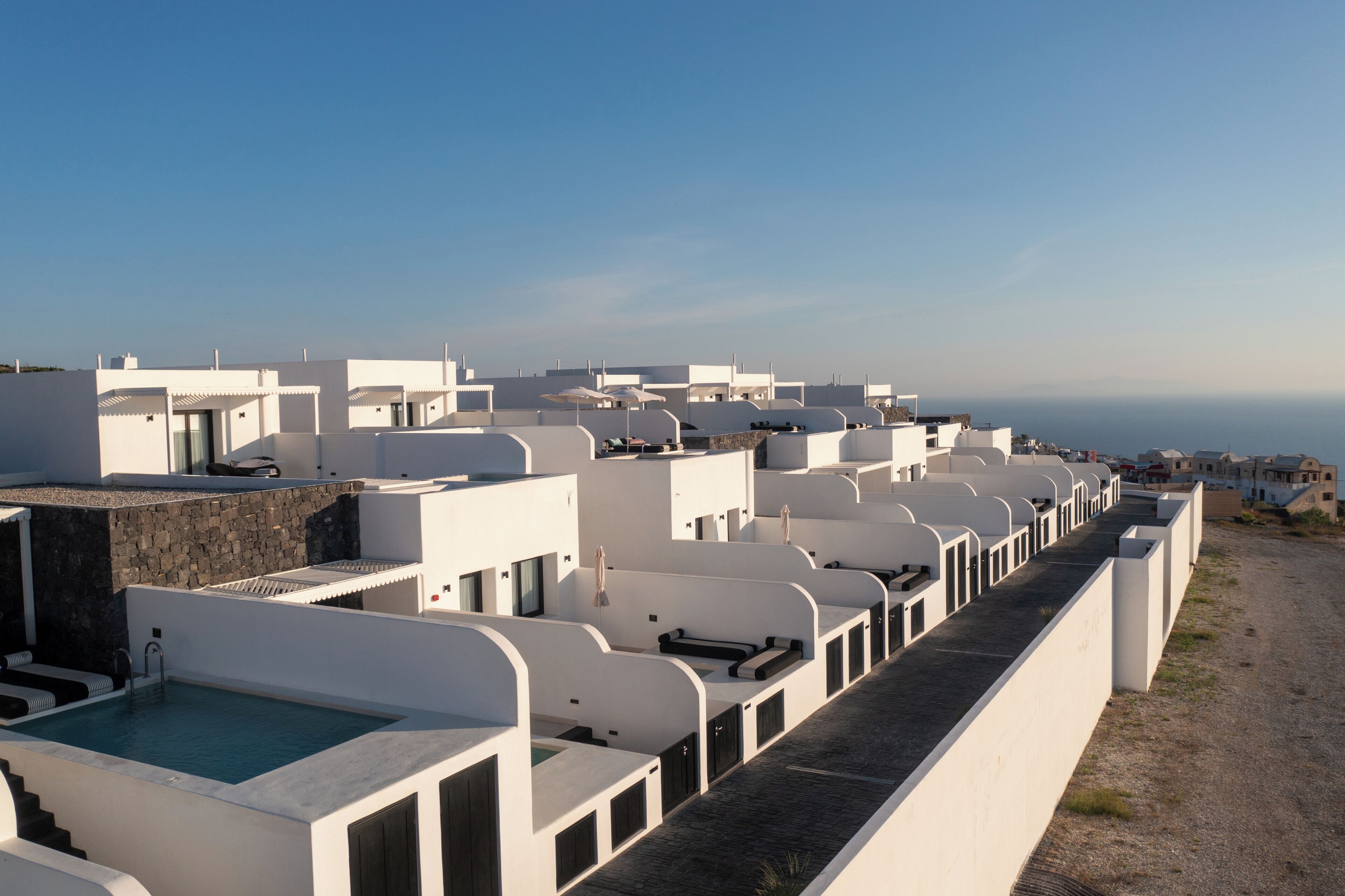 Filas de edificios blancos con piscina y vista despejada al mar.