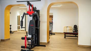 Un gimnasio con equipamiento de levantamiento de pesas, suelo de madera y diseño con arcos abiertos.