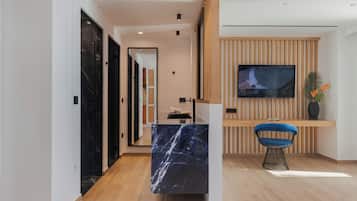 A modern interior with a marble reception desk, a wooden wall panel, a television, and a blue chair.