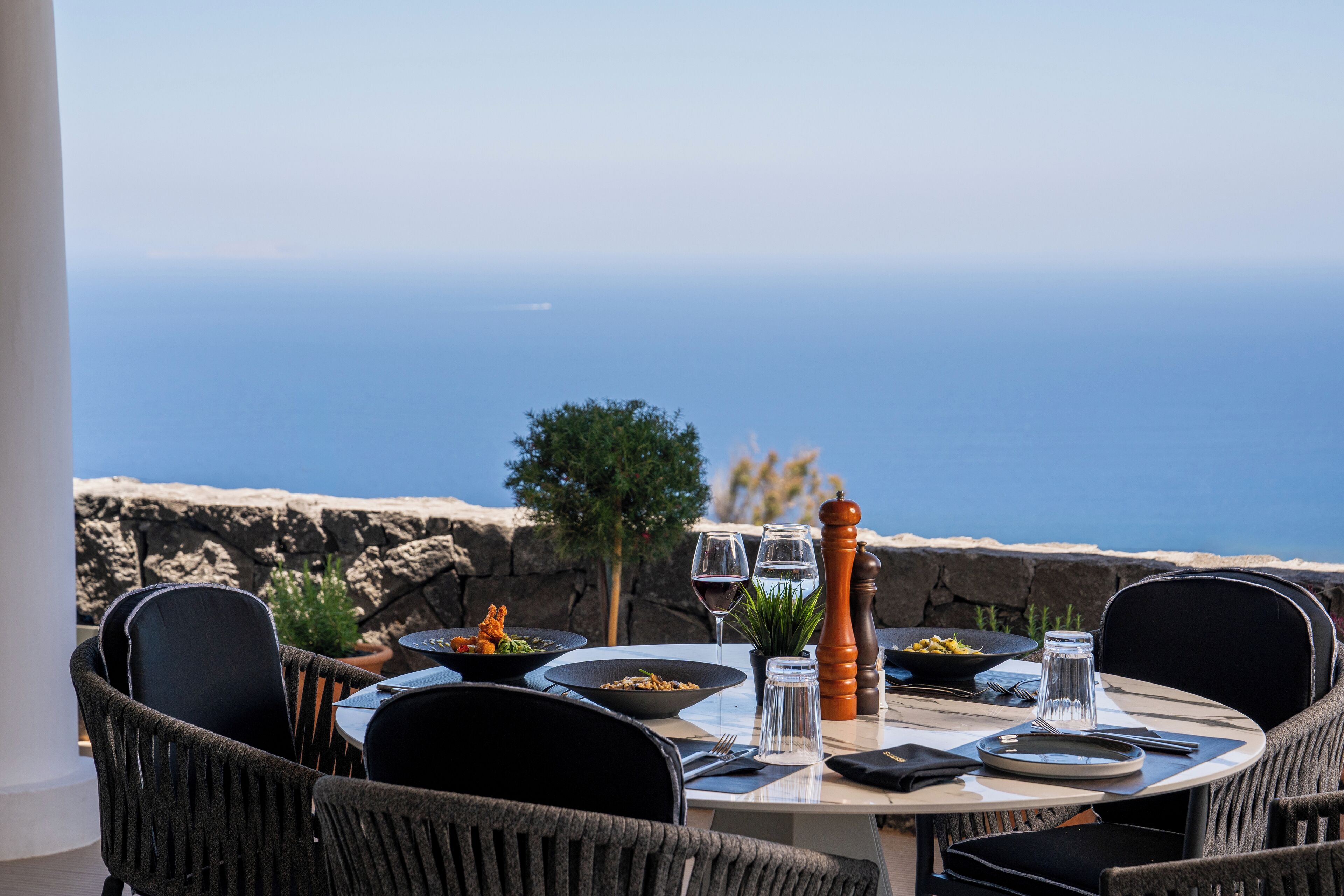 A table set for dining with a view of the ocean.