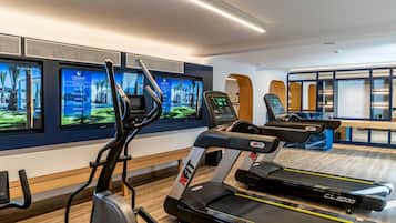 A modern gym with treadmills, an elliptical, and a TV displaying fitness programs.