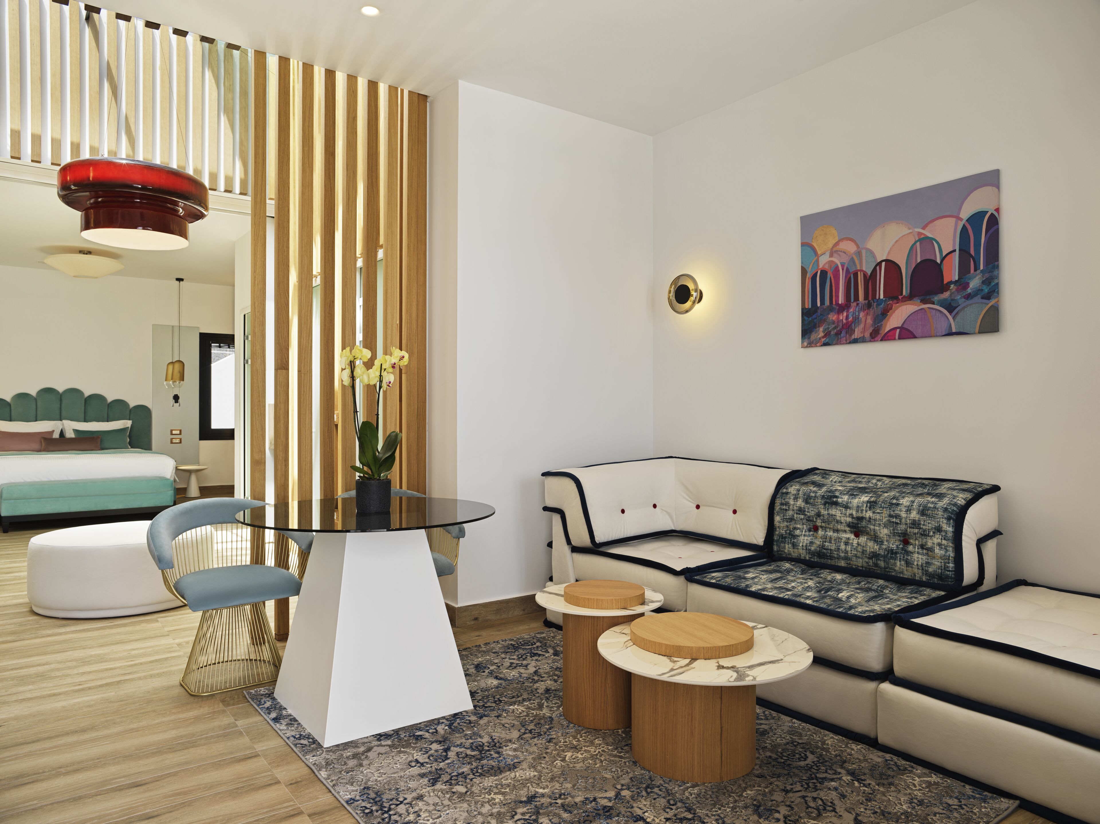A modern living room with a glass-top coffee table, a sofa, and a dining area with a round table.