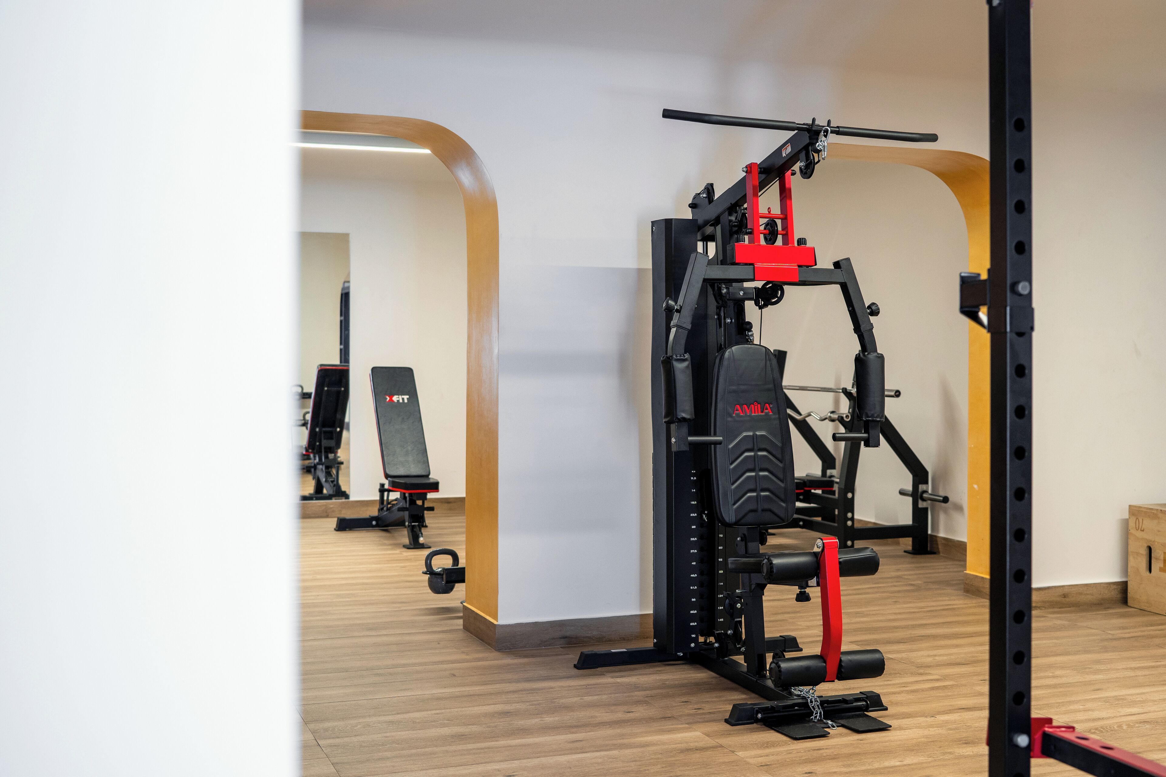 Un gimnasio con diverso equipo de ejercicio, incluyendo una banca y una estructura para sentadillas.