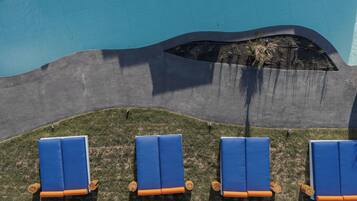 A poolside area with four blue lounge chairs and a small planter with plants.