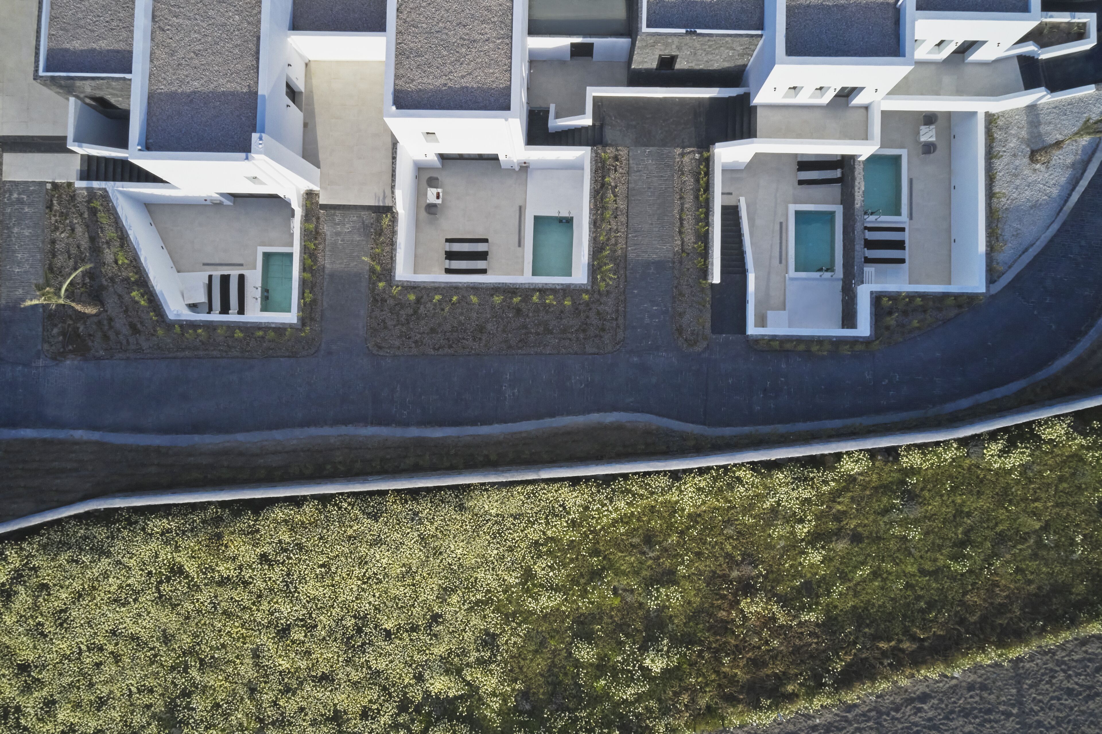 An aerial view of a modern residential building with multiple levels, balconies, and a swimming pool.