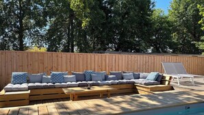 A wooden deck with a built-in seating area and a pool.