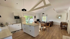 A spacious kitchen with a central island, wooden flooring, and a dining area with a table and chairs.