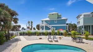 A pool area with a curved pool, lounge chairs, and a dining table. - 🌊Updated Vintage Beach House-Private Pool, Steps to Beach-Blue Lizard🦎 (Fort Myers Beach)
