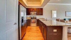 Una cocina moderna con armarios de madera oscura, electrodomésticos de acero inoxidable y encimera de mármol.