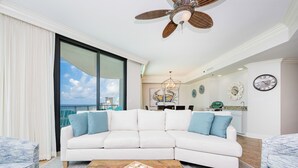 A modern living room with a white sectional sofa, a wooden coffee table, and a ceiling fan.