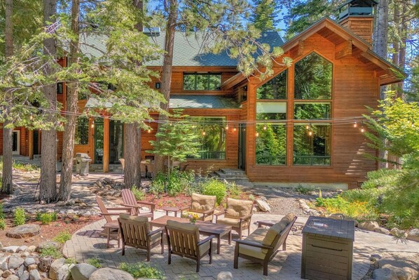 A wooden cabin with a patio area featuring outdoor furniture and a stone pathway.