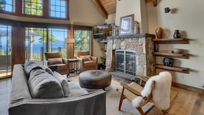 Amplia sala de estar con chimenea, ventanas grandes y vistas al exterior.