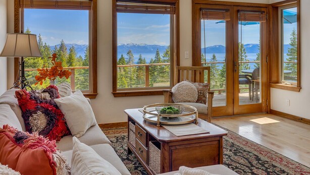 A spacious living room with a large window offering a mountain view, a cozy sofa, and a wooden coffee table. - Sierra Vista - Lakeview - TLUXP (Tahoe City)