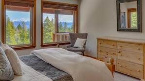 A bedroom with a bed, a chair, a dresser, and two windows with a view of trees and mountains. - Sierra Vista - Lakeview - TLUXP (Tahoe City)
