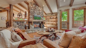 Un salon chaleureux avec une cheminée en pierre, des canapés en cuir et une table basse en bois.