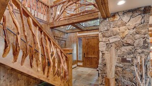 Un escalier en bois au design original, un mur en pierre et une vue sur l’espace intérieur.