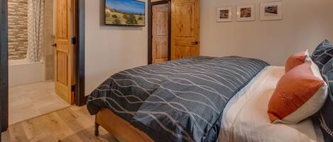 Un dormitorio con cama, vigas de madera en el techo, ventilador de techo y un ventanal grande.