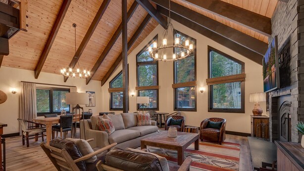 Un salón amplio con techo alto, ventanas grandes, chimenea y un rincón de estar acogedor.