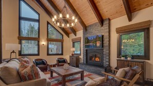 Un salón amplio con chimenea, ventanas grandes y un techo alto.