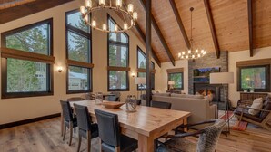 Un amplio espacio de sala con una mesa de comedor de madera, asientos cómodos, ventanas grandes y una chimenea.